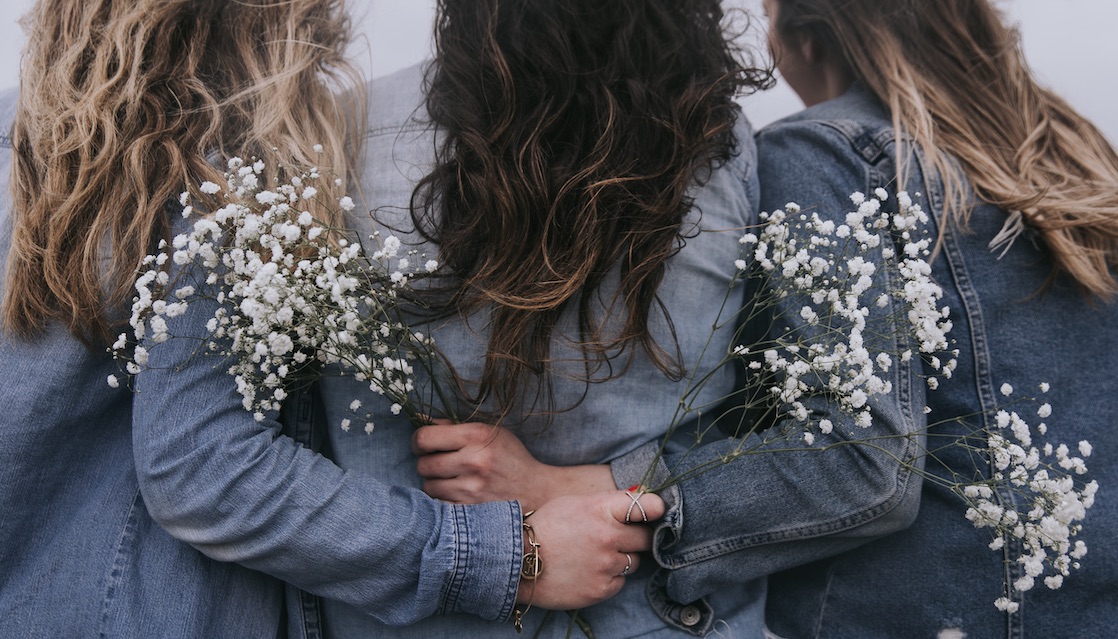 3 Women Arm in Arm With Flowers